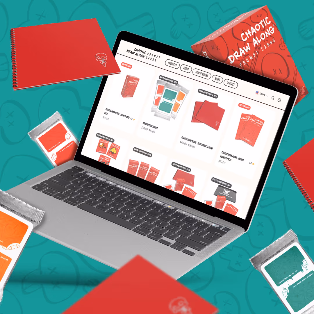 Laptop showing the Chaotic Draw Along online store's product listing page, surrounded by the brand's red spiral notebooks and foil-wrapped card packs.